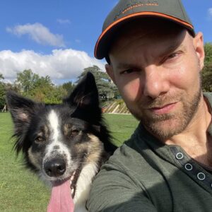Homme et chien souriants dans un parc verdoyant.